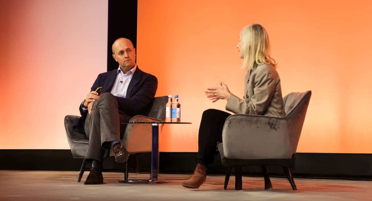 Two people speak on stage.